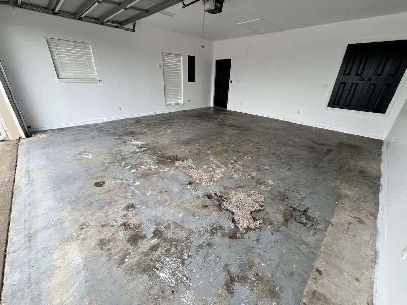 Worn concrete floor in garage with white walls and black doors